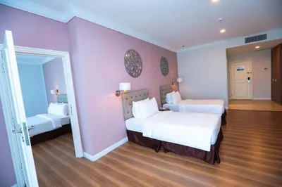 a bedroom with two beds and a pink wall at Hotel Casuarina@Kuala Kangsar in Kuala Kangsar