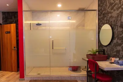 a glass shower in a bathroom with a red wall at Attic Hotel in George Town