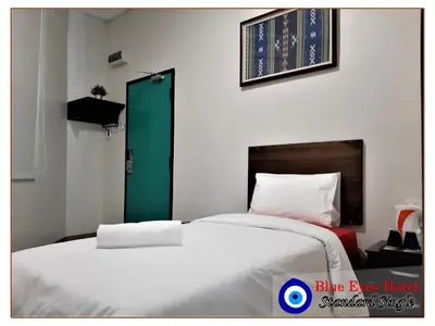 two beds in a room with a green door at Blue Eyes Hotel in Kepala Batas