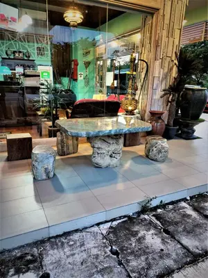 a stone bench sitting in front of a store at Blue Eyes Hotel in Kepala Batas