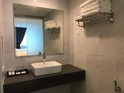 a bathroom with a sink and a mirror and towels at Dandelion Inn in Simpang Pulai
