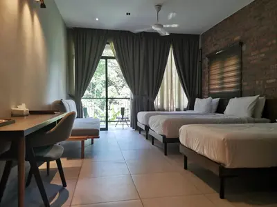 a hotel room with three beds and a desk at Sementra Hot Spring Nature Resort in Gopeng