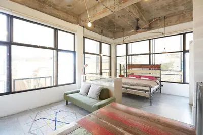 a bedroom with a bed and a couch and windows at Belakang KongHeng By DreamScape in Ipoh
