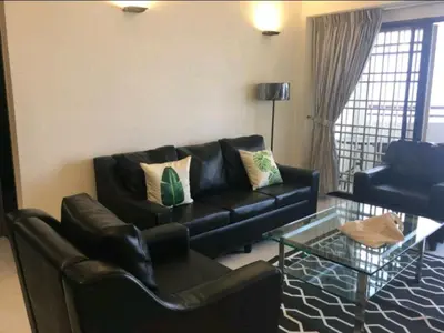 a living room with a black couch and a glass table at Deluxe VIP Seaview Batu Ferringhi 1503 - 3 Rooms in Batu Ferringhi