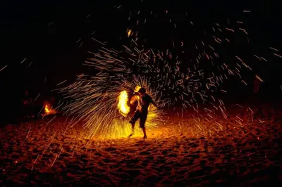 a man standing on a beach with a fire at Deluxe VIP Seaview Batu Ferringhi 1503 - 3 Rooms in Batu Ferringhi