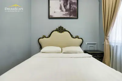 a bedroom with a white bed with a gold headboard at Zetter Suites by Dreamscape in Cameron Highlands