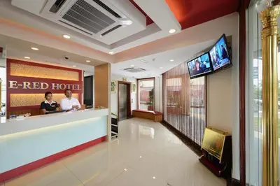 a red hotel lobby with two people at a counter at ERNES Hotel Bayu Mutiara in Bukit Mertajam