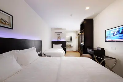 a hotel room with two beds and a flat screen tv at ERNES Hotel Bayu Mutiara in Bukit Mertajam