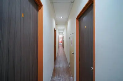 a hallway with wooden doors and a long corridor at Hotel O V Stay Guesthouse in Ayer Itam