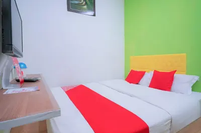 a bedroom with a bed with red pillows and a television at Hotel O V Stay Guesthouse in Ayer Itam