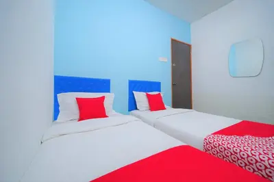 two beds with red and white pillows in a room at Hotel O V Stay Guesthouse in Ayer Itam