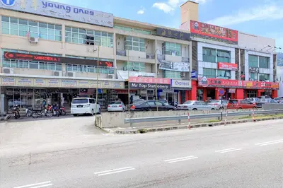a building with cars parked in front of a street at Hotel O V Stay Guesthouse in Ayer Itam