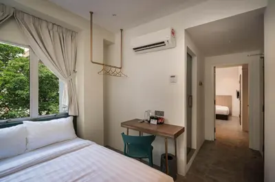 a bedroom with a bed and a desk and a window at Masson Hotel Butterworth in Perai