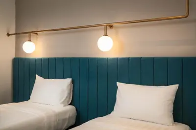 two beds with white pillows and two lights above them at Masson Hotel Butterworth in Perai