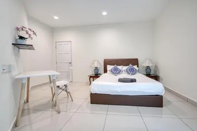 a bedroom with a bed and a desk with two lamps at Profolio @ Mansion One in George Town