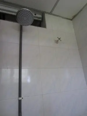 a shower with a faucet on a white tile wall at Happy Owl in Ipoh