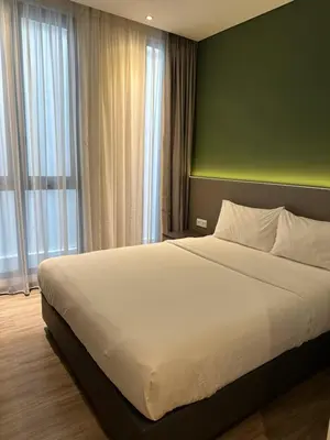 a bedroom with a large white bed with a green wall at The Gallivant Hotel in George Town
