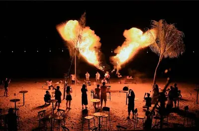 a group of people standing on a beach with fire at EXECUTIVES Pantai Seaview Batu Ferringhi 2704 - 2 Bedrooms in Batu Ferringhi