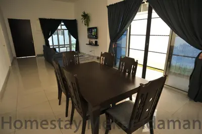 a dining room with a wooden table and chairs at homestay mekar idaman in Kepala Batas