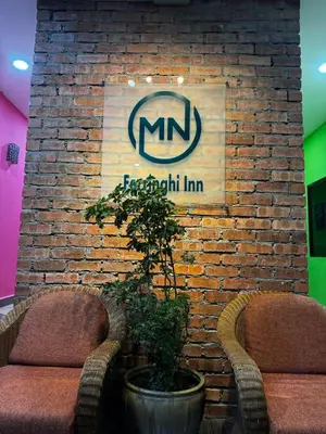a sign on a brick wall with two chairs at MN Ferringhi Inn in Batu Ferringhi