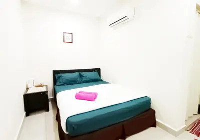 a bedroom with a bed with a blue and pink pillow at MN Ferringhi Inn in Batu Ferringhi