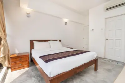 a white bedroom with a bed and a night stand at Pantai Seaview Resort Batu Ferringhi 1801 - 3 Rooms in Batu Ferringhi