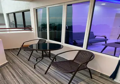 a room with a table and chairs and a balcony at My Suites Sri Sayang Resort in Batu Ferringhi