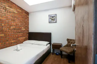a bedroom with a bed and a chair and a brick wall at URBANSTAY AT IPOH (STANDARD ROOM) in Ipoh
