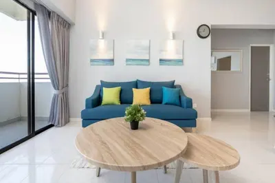 a living room with a blue couch and a table at VIP Suite Seaview Resort Batu Ferringhi 1202 - 3 Rooms in Batu Ferringhi