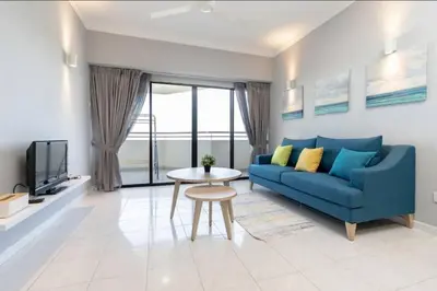 a living room with a blue couch and a table at VIP Suite Seaview Resort Batu Ferringhi 1202 - 3 Rooms in Batu Ferringhi