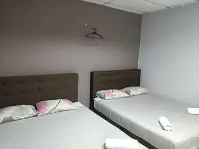 two beds in a room with white walls at Hotel Tropicanna Pulai Point in Ipoh