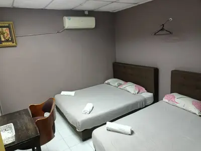 a room with two beds and a chair and a desk at Hotel Tropicanna Pulai Point in Ipoh