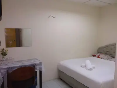 a room with a bed and a table and a mirror at Hotel Tropicanna Pulai Point in Ipoh