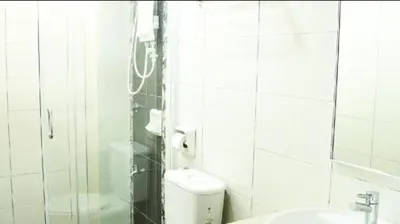 a white tiled bathroom with a toilet and a sink at Marina Height Seaview Resort, Teluk Batik, Lumut in Kampong Tebing Rabak