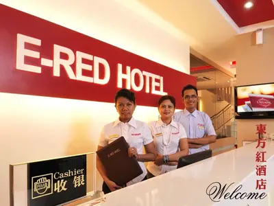 three men standing in front of a red hotel sign at ERNES Hotel in Perai