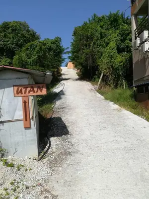a dirt road with a sign on the side at Utan Teluk Nipah in Pangkor
