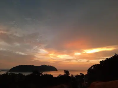 a sunset over a body of water with an island at Utan Teluk Nipah in Pangkor