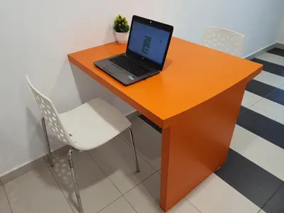 a laptop computer sitting on top of a orange desk at Explore The World at The CEO Studio Penang in Bayan Lepas