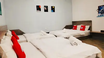 a room with three beds with white sheets and red pillows at Winggarden Murals House by JE Boutique Guesthouse in Ipoh