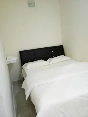 a bedroom with two white beds and a black headboard at 28 Gred Hotel in Bukit Mertajam