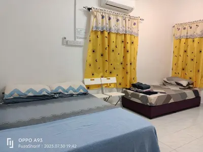 a bedroom with two beds and yellow curtains at FAFA ROOMSTAY TANJUNG MALIM in Tanjung Malim