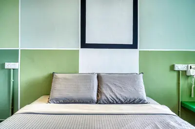 a bed with two pillows in a green and white room at Parkland Express in Brinchang