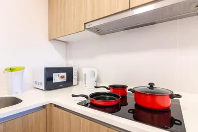 a kitchen with two pots on a stove with a microwave at ❈ Tropicana 218 by ALV Suites ❈ in George Town