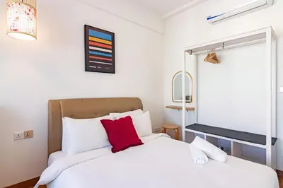 a bedroom with a white bed with a red pillow at ❈ Tropicana 218 by ALV Suites ❈ in George Town