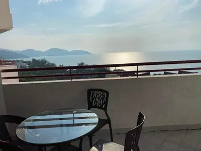 a table and chairs on a balcony with a view of the ocean at The View Ferringhi 3BR Apartment in Batu Ferringhi