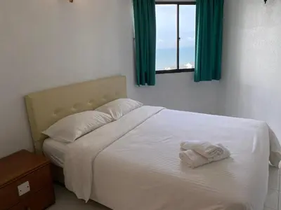 a bedroom with a white bed with a window at The View Ferringhi 3BR Apartment in Batu Ferringhi