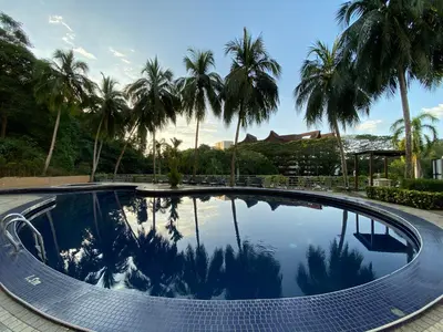 a swimming pool with palm trees in the background at The View Ferringhi 3BR Apartment in Batu Ferringhi