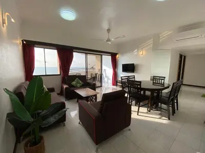 a living room with a couch and a table and chairs at The View Ferringhi 3BR Apartment in Batu Ferringhi