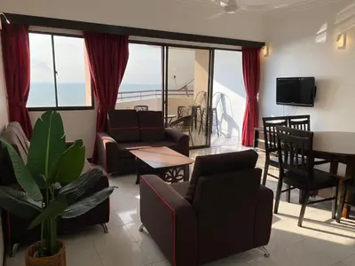 a living room with chairs and a table and a balcony at The View Ferringhi 3BR Apartment in Batu Ferringhi