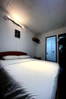 a bedroom with a large white bed and a mirror at Madani Muslim Hotel Cameron Highland in Cameron Highlands